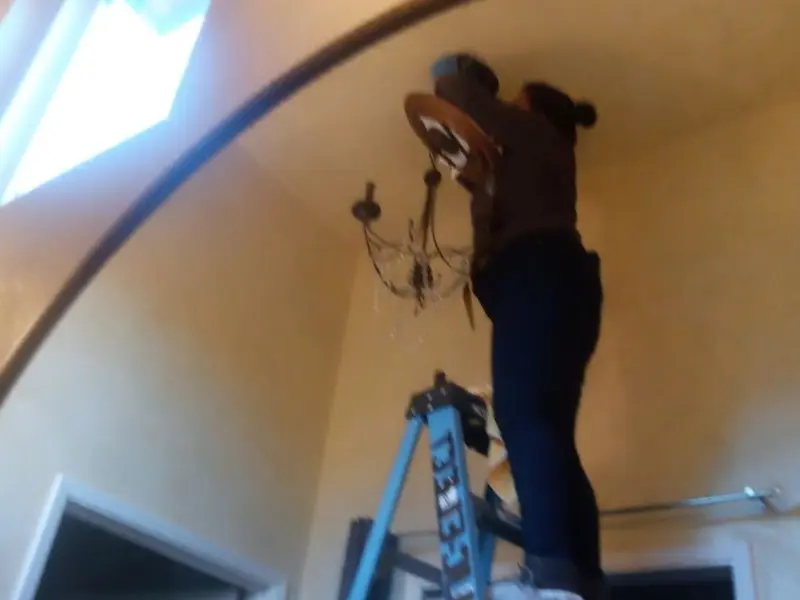 Electrician installing a chandelier in a Seattle residence